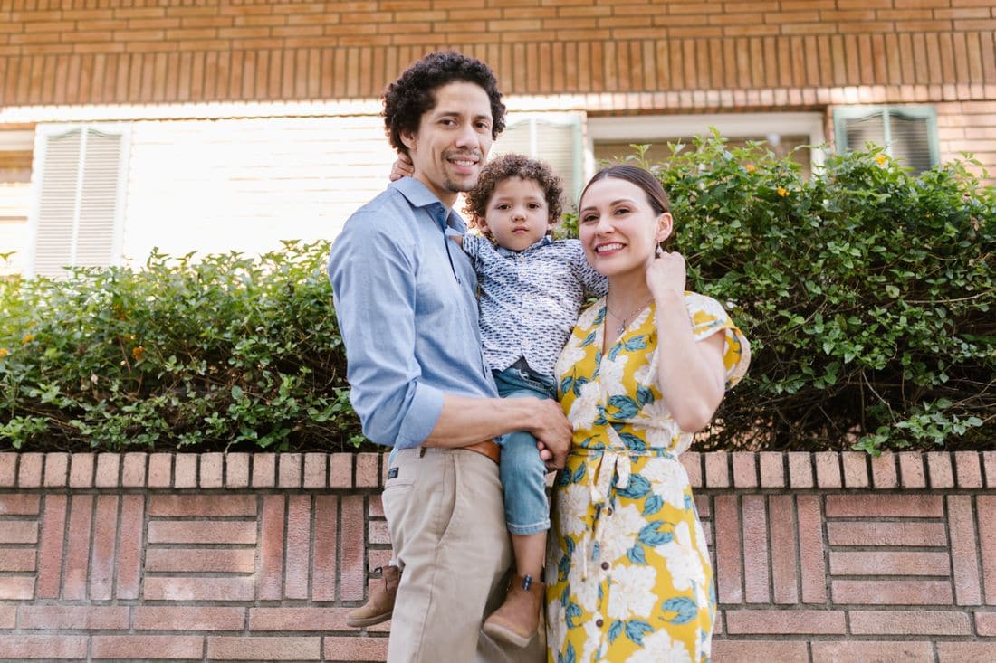 A young family smiling together outside their home