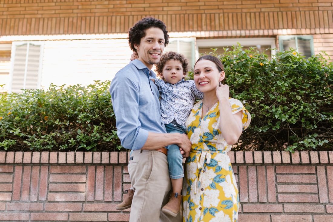 A young family smiling together outside their home