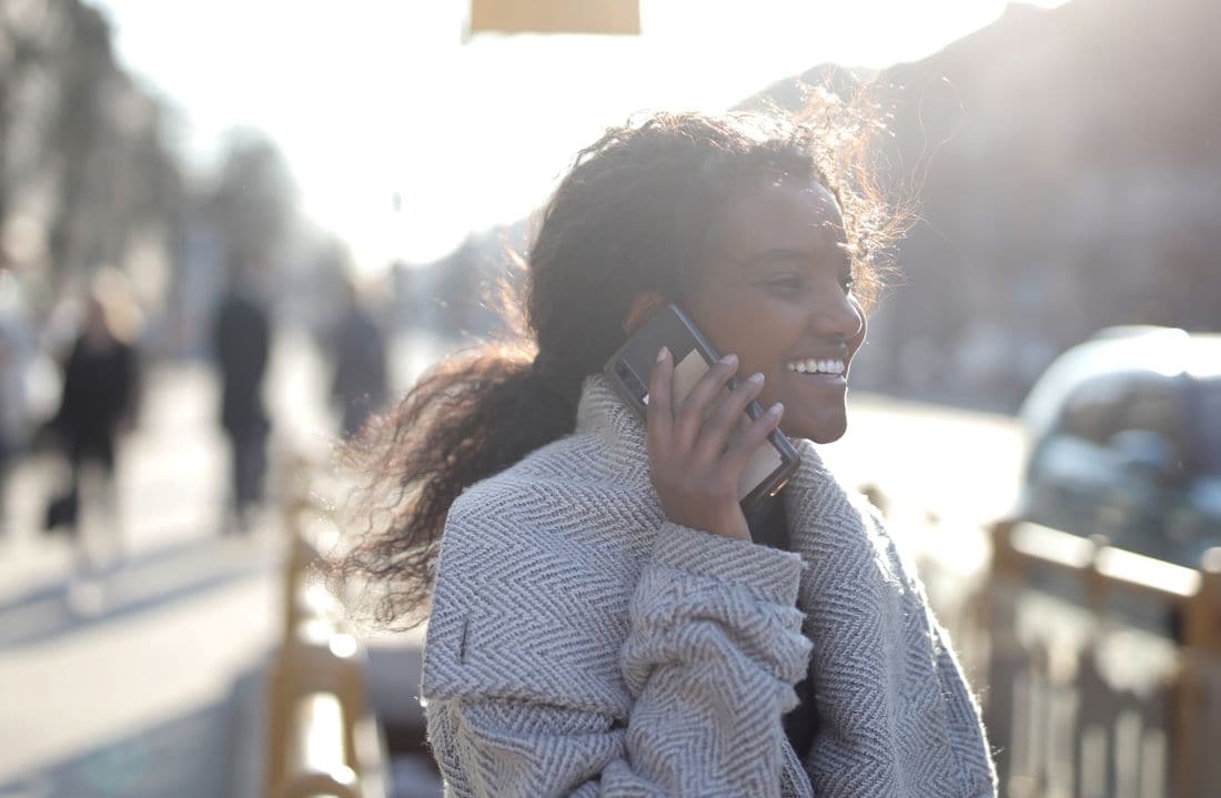 A woman smiling during a phone call in warm morning light